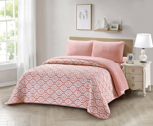 A blush pink diamond quilted bedding set with a 3D embossing pattern, displayed on a bed with additional details like pillows and bed frame visible in the background.