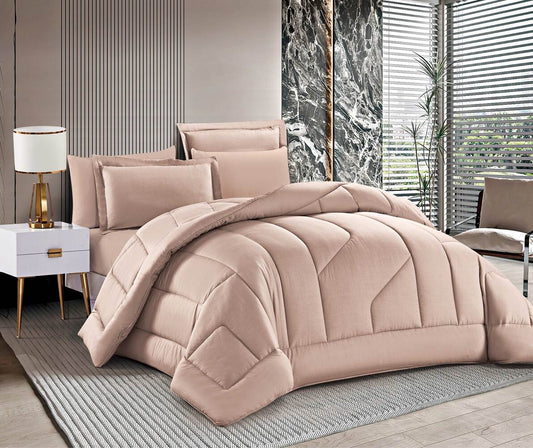 A mocha-colored, quilted summer comforter set displayed on a bed, with additional pillows and a duvet cover visible.