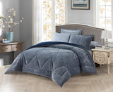 A charcoal grey quilted bedding set on a king-sized bed, with two additional pillows on the bed, placed in a room with a nightstand and a lamp on either side of the bed.