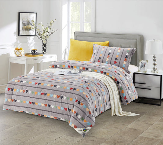 A quilted comforter set with a heart print, displayed in a bedroom setting with accompanying pillows, bedskirt, and decorative items.