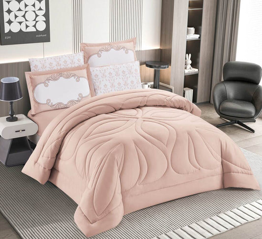A blush pink quilted bedding set with a 3D diamond stitch design displayed on a bed, including two pillowcases.