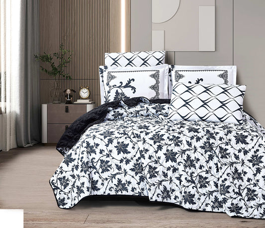 Bed with black and white floral bedding in a bedroom setting.