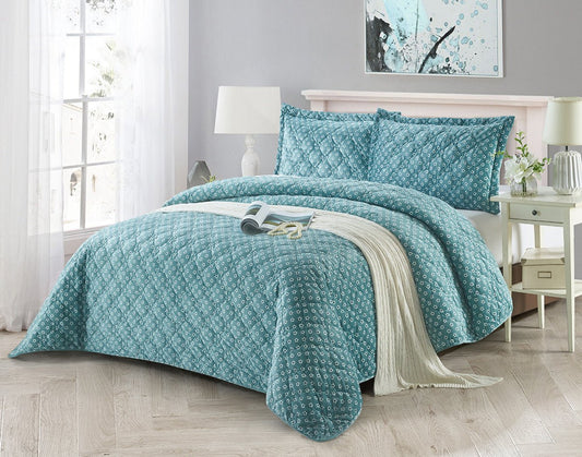 A floral checkered quilted comforter set in blue and white, displayed on a bed with additional details like pillows, bed frame, and room decor.