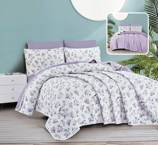 Floral bedding set with purple accents on a bed in a room with a light blue wall.