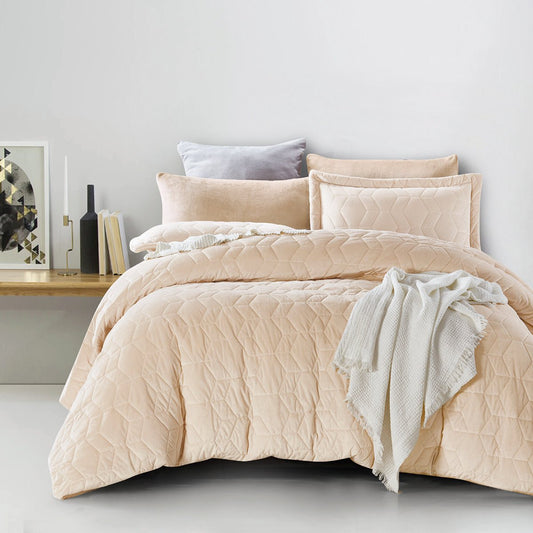 A beige grid quilted comforter set on a bed, with additional pillows and a blanket draped over the side of the bed.