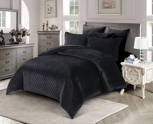 A black quilted comforter set displayed on a bed in a bedroom setting, including a king size comforter, two pillow shams, and a bed skirt.