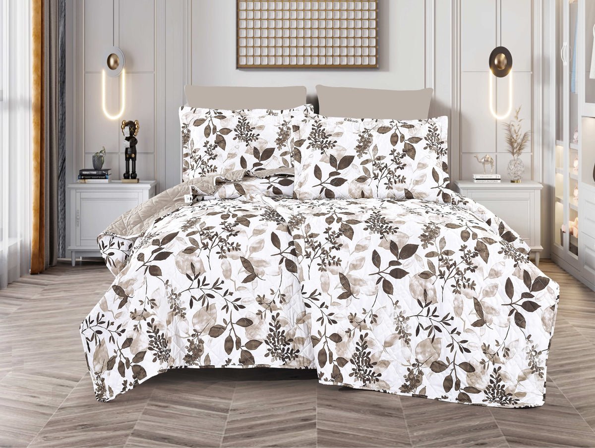 A bed with a white spread featuring a green and brown leaf print, displayed in a room with decorative lighting and a framed picture on the wall.