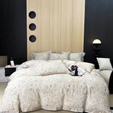 A luxury duvet cover set with a floral pattern, displayed on a bed in a bedroom setting with wooden headboard and bedside tables.
