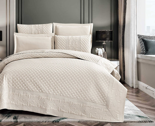 Beige quilted coverlet set on a bed in a bedroom setting.