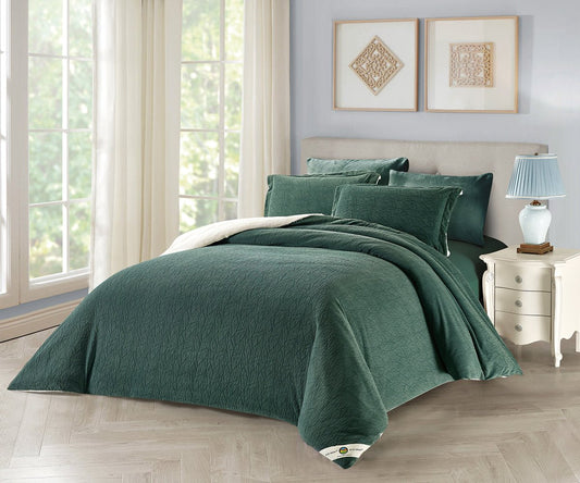 A leaf green botanical comforter set on a bed, with additional pillowcases displayed against a wall, in a room with a window and a lamp.