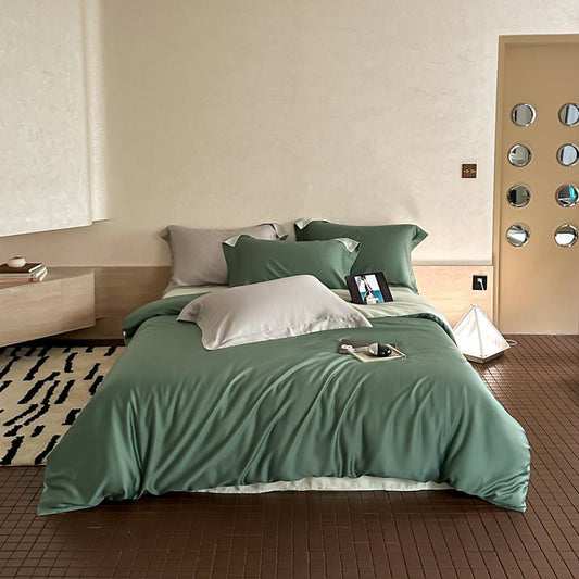 A green duvet cover set on a bed in a bedroom setting with pillows, bedsheet, and a remote control visible.