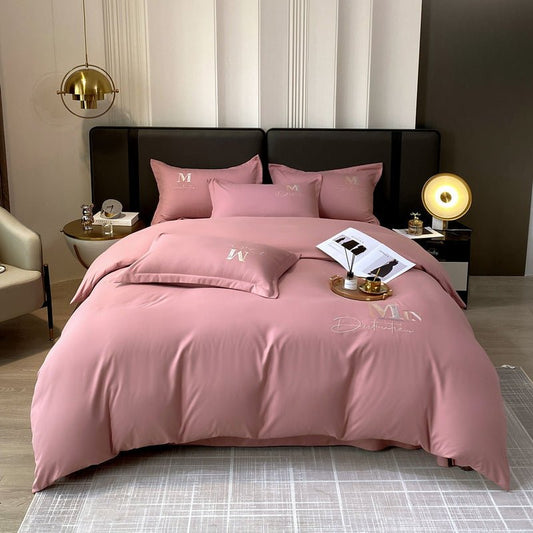 A pink duvet cover set with embroidered details on a bed in a bedroom setting, including pillows and a comforter.
