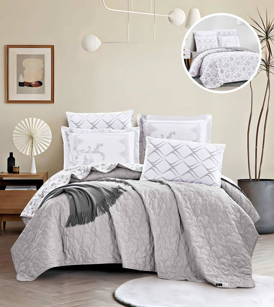 A bed with a gray quilt and matching pillows, displayed in a room with a minimalist decor. A close-up inset shows a detailed pattern on the bedding.