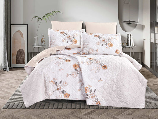 A white bedding set with a floral patchwork design, displayed on a bed in a room with a light interior.
