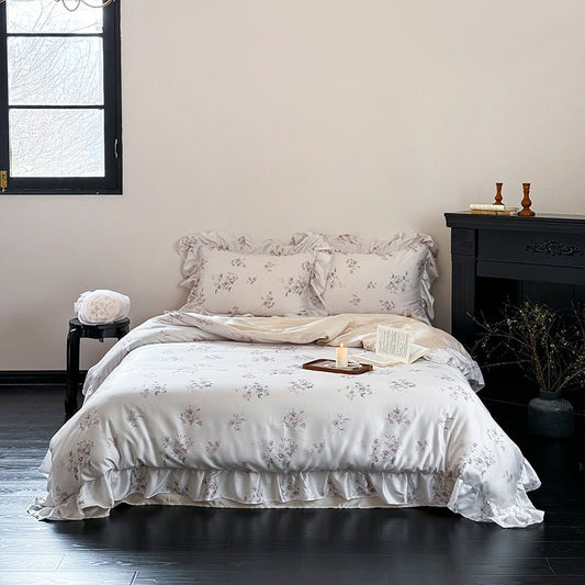 A duvet cover set with floral embroidery displayed on a bed in a room with a window, a side table, and a decorative fireplace.