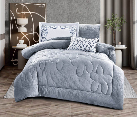 A quilted grey comforter set with matching pillows displayed on a bed in a bedroom setting.