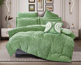 An emerald green quilted flannel comforter set on a bed, with additional pillows and a comforter draped over the edge of the bed, presented in a room setting.