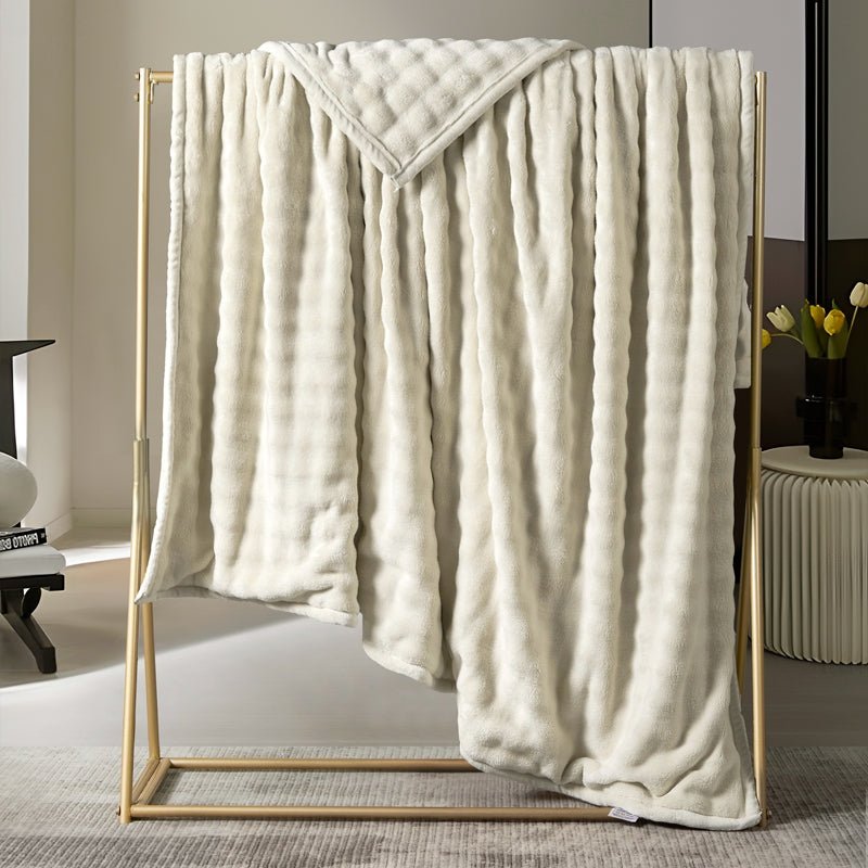 A beige travel nap blanket with sleeves displayed on a frame, in a room setting with decorative elements.