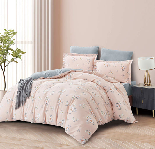 Floral bedding set on a bed in a bedroom with a lamp and plant.