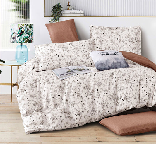 Floral patterned bedding set on a bed with pillows and a lamp in the background.
