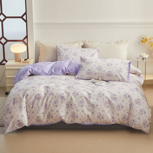 A pastel floral cotton duvet cover set on a bed, with one pillow and a duvet cover displayed, set against a home bedroom backdrop with bedside tables and lamps.