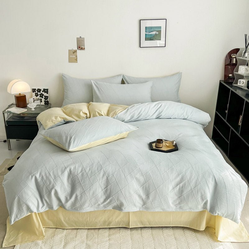 A bedroom with a bed dressed in a blue and white 3D textured cotton duvet cover set, accompanied by matching pillows and a bed skirt, with a side table and lamp.