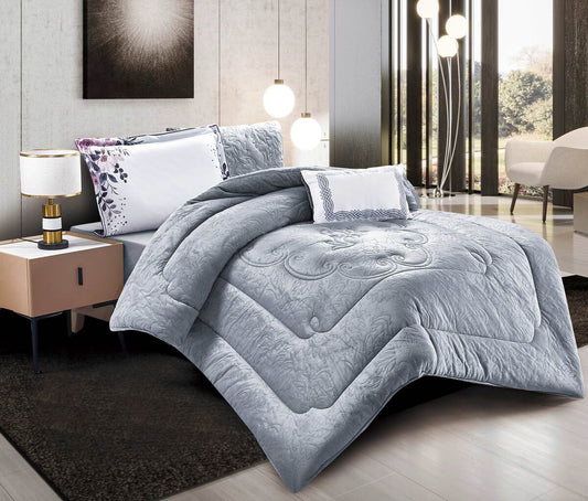 A gray quilted comforter set on a bed, with accompanying pillow shams and decorative pillows, presented in a bright room setting.