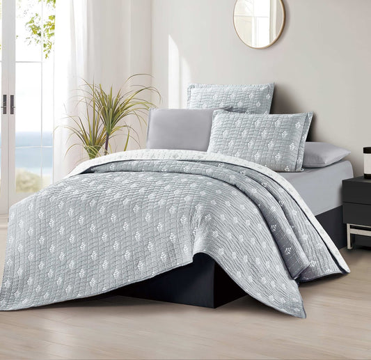 A floral patterned bedding set in gray and white, displayed on a bed with pillows and a comforter.