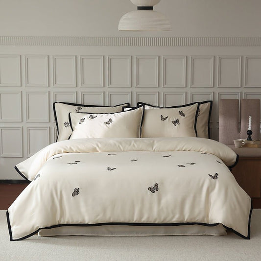 A beige duvet cover set with embroidered corners featuring a floral pattern, displayed in a bedroom setting.