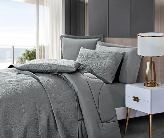 A gray comforter set with geometric floral embroidery, displayed on a bed in a bedroom setting, including a pillowcases and a duvet cover.