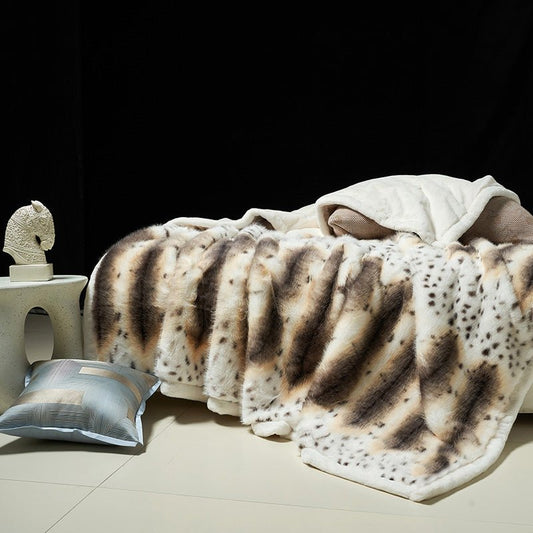 A blanket with a animal print, possibly a leopard or cheetah print, draped over a bed with a matching pillow beside it.