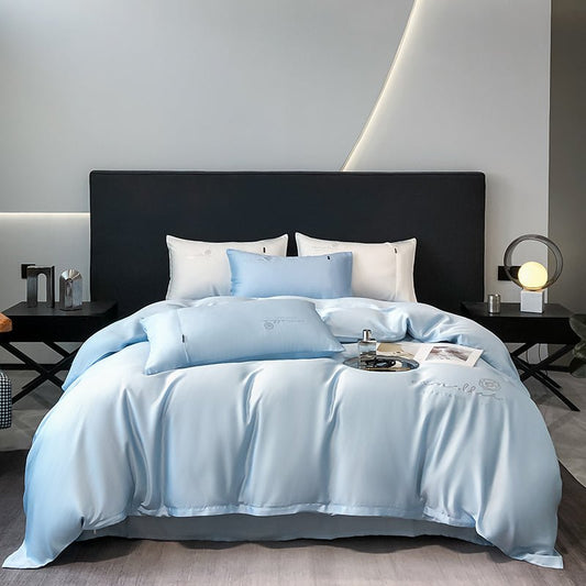 A blue Tencel duvet cover set on a bed, with a crystal-embossed design, displayed in a bedroom setting with bedside tables and lamps.