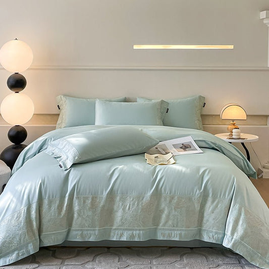A green long staple cotton duvet cover set displayed on a bed in a bedroom setting with bedside tables and lamps.