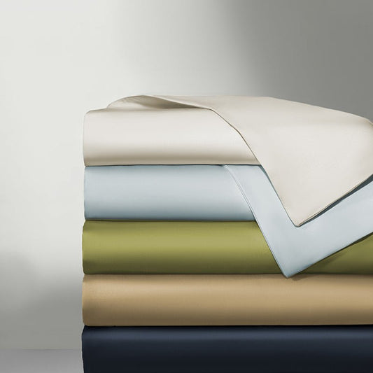 A stack of folded hybrid tencel fitted sheets in various colors including beige, green, blue, and gray.