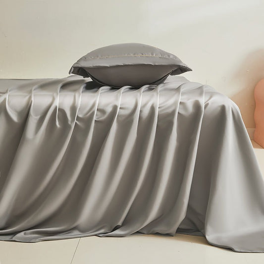 A gray silk duvet cover displayed on a bed with a pillow placed on top.