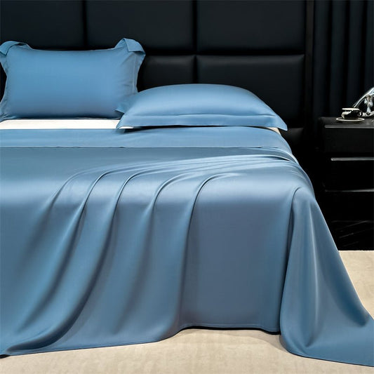 A blue silk bed sheet set on a bed, with pillowcases and a flat sheet displayed in a room with dark furniture.