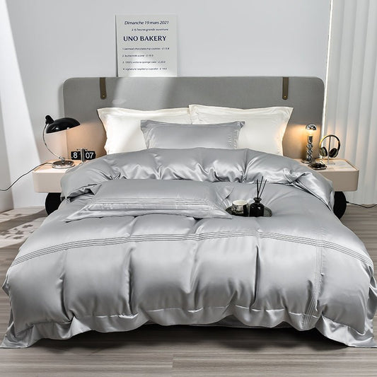 A gray Tencel duvet cover set on a bed, with a duvet, pillowcases, and a comforter cover, presented in a room setting with bedside tables and lamps.