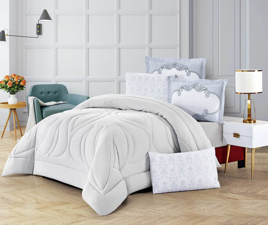 A white comforter set with floral quilted design, displayed in a bedroom setting with matching pillows and bedsheet.