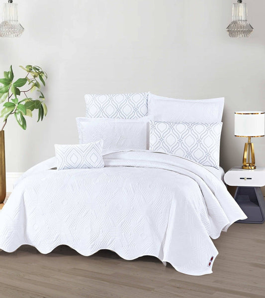 A white bedspread with a geometric diamond pattern displayed on a bed, accompanied by matching pillows.