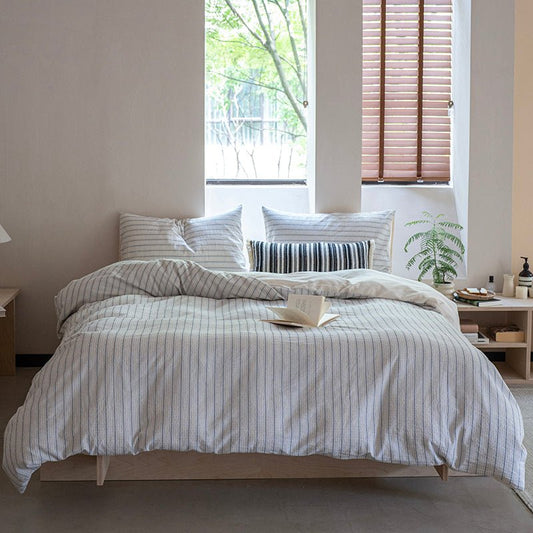 A striped cotton duvet cover set on a bed in a room with window in the background.