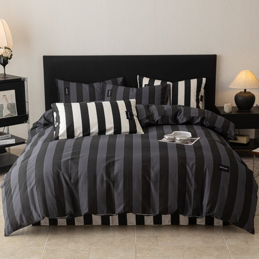 A bedding set with navy and black stripes, displayed on a bed with other pillows and a magazine on the bed's surface.