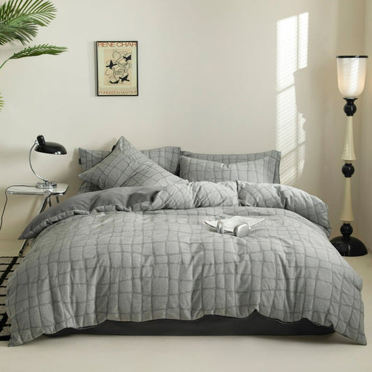 A brown square weave cotton bedding set on a bed, with additional pillows placed beside the bed. The room setting includes decorative items such as a framed picture on the wall, a lamp, and a plant.