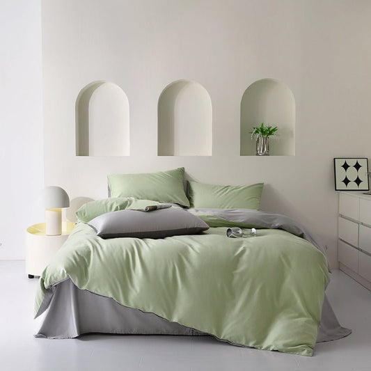 A mint green cotton bedding set on a bed, with additional pillows and bed sheets arranged neatly. The room has a minimalist design with a white color scheme and decorative wall niches.