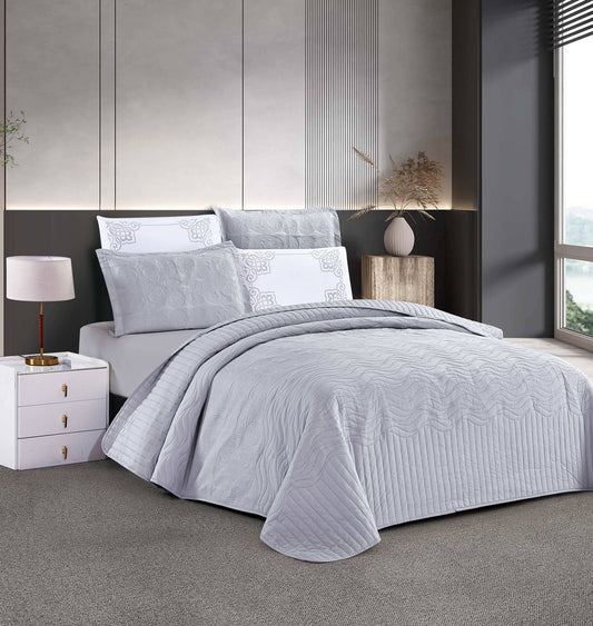 A striped bedspread in gray color, displayed on a bed with pillows, in a room with modern decor.