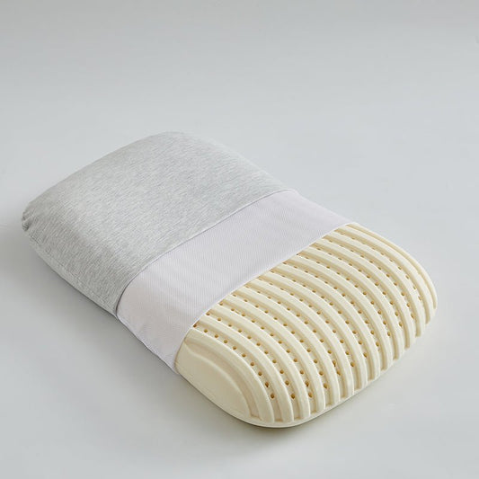 A white, ergonomic latex pillow with a textured surface, partially covered by a gray fabric.