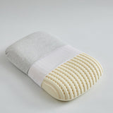 A white, ergonomic latex pillow with a textured surface, partially covered by a gray fabric.