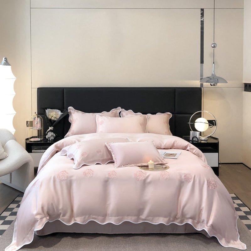 A pink Tencel duvet cover set on a bed, with decorative pillows and a ruffled comforter edge, in a stylishly decorated bedroom setting.