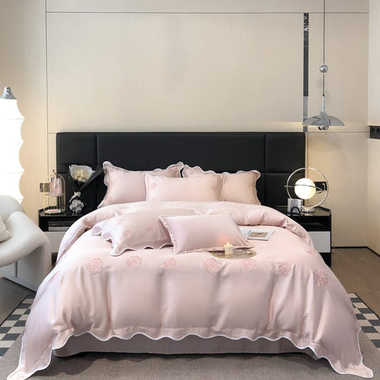 A pink Tencel duvet cover set on a bed, with decorative pillows and a ruffled comforter edge, in a stylishly decorated bedroom setting.