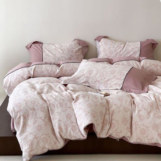 A pink floral duvet cover set on a bed, with matching pillows and comforter.