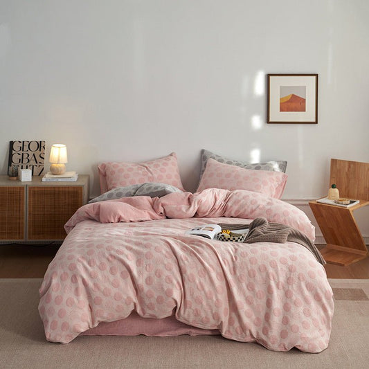 A double gauze duvet cover set in pink with a geometric pattern, displayed on a bed in a bedroom setting.
